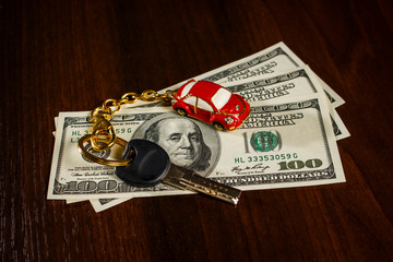 Key with a keychain in the form of a car on dollars