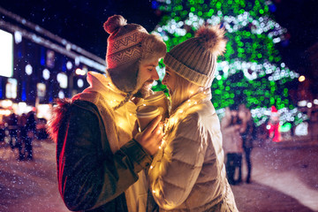Adult couple hanging out in the city during Christmas time over lights city background and snow at...