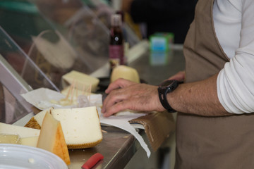 Fototapeta na wymiar Maid who Slices Cheese in a Food Store