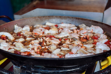 Seafood stew in a frying pan. Close up of fresh fish fillets and prawns cooked in a stew with vegetables.
