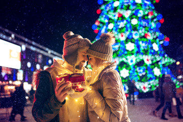 Adult couple hanging out in the city during Christmas time over lights city background and snow at night