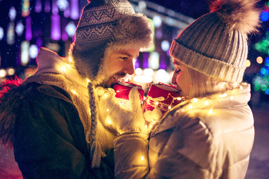 Adult Couple Hanging Out In The City During Christmas Time Over Lights City Background And Snow At Night