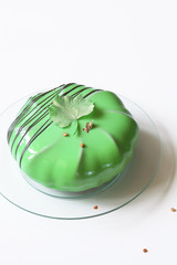 Contemporary Chocolate Almond Mousse Cake, covered with Green Mirror Glaze, on white background.

