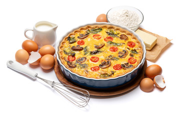 Baked homemade quiche pie in ceramic baking form, eggs and cream
