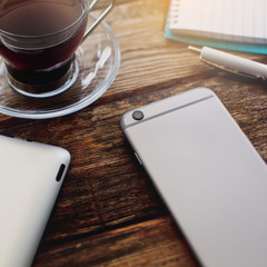 Smartphone and cup of tea on the wooden table.
