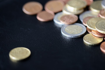 A pile of euro coins scattered on a dark surface close up