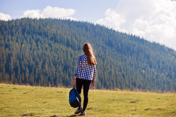 Back view young woman with backpack on top of mountains looking to nature