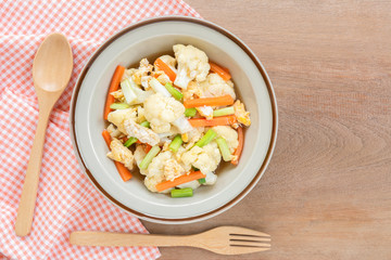 top view of stir fried cauliflower and egg in a ceramic dish on wooden table. asian homemade style food concept.