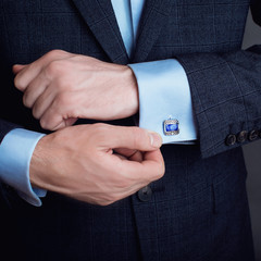 Close-up of a man in a tux fixing his cufflink. groom bow tie cufflinks