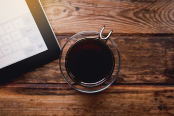 Smartphone and cup of tea on the wooden table.