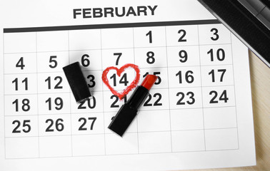 Valentines day and Holidays concept. Calendar sheet with 14th february date marked by red heart shape with red lipstick. Close up