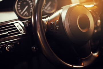 Steering wheel in a new car. Steering wheel with control buttons. Modern car interior in black color.