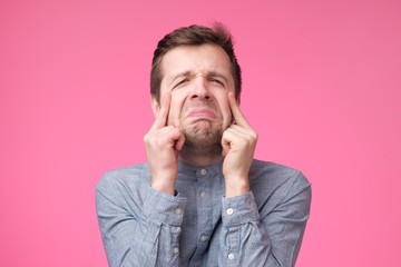 sad young man crying on pink background