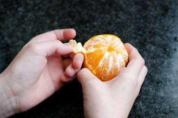 Childs hands peeling a tangering