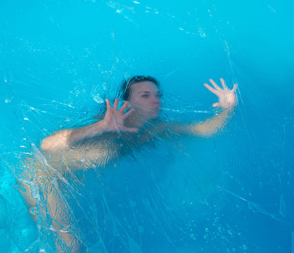 Fototapeta Young nude woman posing in polyethylene film under the water