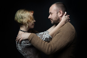 Romantic loving married couple 30-40 years old against a dark background.