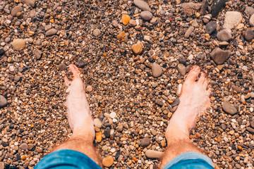 Sea wave washes feet on the beach of pebbles