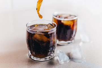 Closeup of two glasses of cola with ice - harmful drink