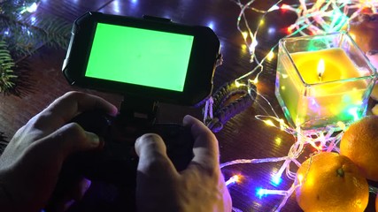 Game Pad with smartphone in man hands in action, on black background with, colorful lights, Christmas New Year Composition. Smartphone gaming video game. Green screen. Gifs, gift. top view, play