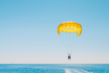 Two people on a parachute behind the boat - parasailing - resort entertainment