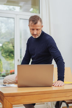 Man sitting on desk and looking at laptop