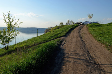 The huge river Dniester flows between high steep hills covered with spring lush green grass against the blue sky