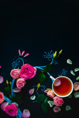 Teacups and flower petals in chalk tree flat lay. Rose tea creative flat lay on a dark background with copy space