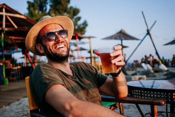 Young man enjoying beer and sunset in a beach bar