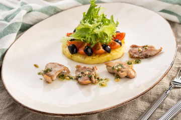 Fried chicken fillets, tomatoes and pineapples on white plate served on the table