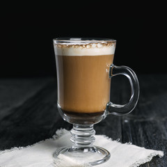 Irish coffee glass with foam and cinnamon on wooden table