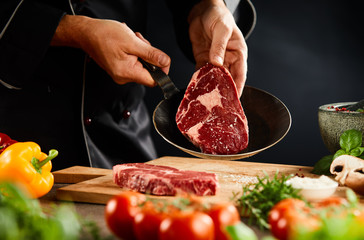 Chef placing a raw steak into a skillet