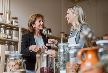 A female shop assistant serving a senior customer in a zero-waste shop.