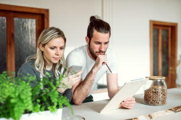 Two shop assistants standing at the counter in zero waste shop, checking stock.