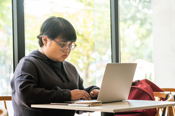 Fat Asian freelancer working on laptop indoor