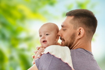 family, parenthood and people concept - father with little baby daughter over green natural...