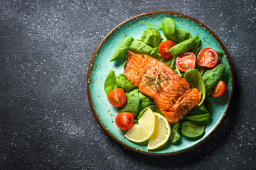 Baked salmon fish fillet with fresh salad top view.