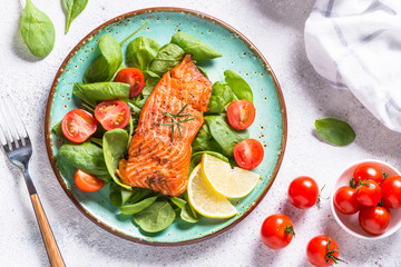Baked salmon fish fillet with fresh salad top view on white.