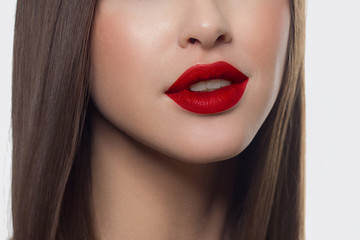 Fototapeta premium Piękno zbliżenie kobiet pełne czerwone usta z błyszczącą skórą i długimi włosami. Pielęgnacja skóry twarzy w salonie spa lub kosmetologii i modny czerwony błyszczyk do ust. Makijaż wieczorowy
