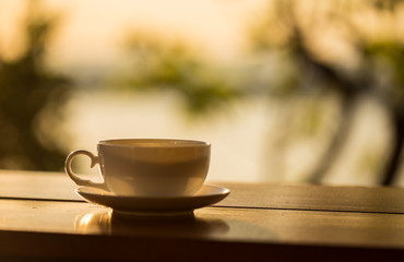coffee cup with sunset background on wood table.
