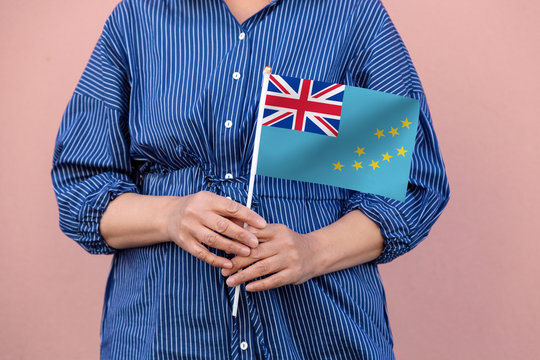 Tuvalu flag. Close up of a woman's hands holding Tuvalu flag.	