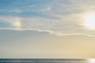 Obraz premium Blue cloudy sky with rainbow effect over the sea on a sunset as a natural background.