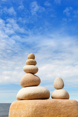 Rock zen pyramid of white stones on a background of blue sky and sea.