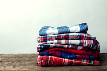 checkered shirts stack on wooden background. closeup.