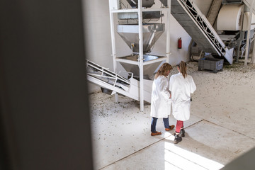 Two women with white coat working in a factory