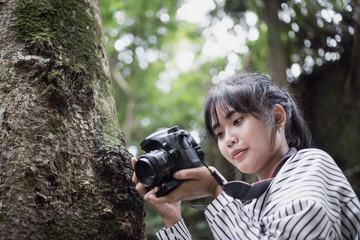 Asian photographer photoshoot working camera. Woman taking photo with smiling for hobby and lifestyle with green trees in forest at outdoor.