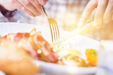 Man eating breakfast with fork and knife, close up