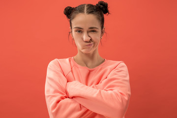 Angry woman looking at camera. Aggressive business woman standing isolated on trendy coral studio...