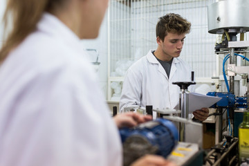 Young caucasian man with white coat working in a factory