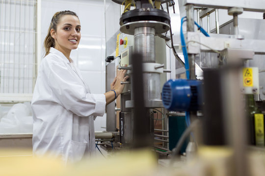 Side view of young woman working in a production line of bottling