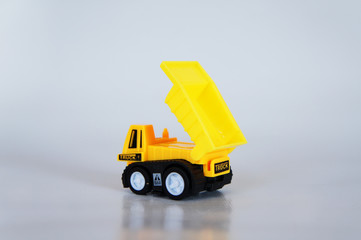 Selective focused on yellow toy dump truck made from plastic. Isolated on white background. 